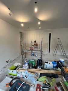 Léon qui peint un mur dans le salon du chantier d'appartement