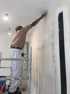 Léon appliquant de l'enduit dans la pièce principale du chantier de rénovation d'appartement